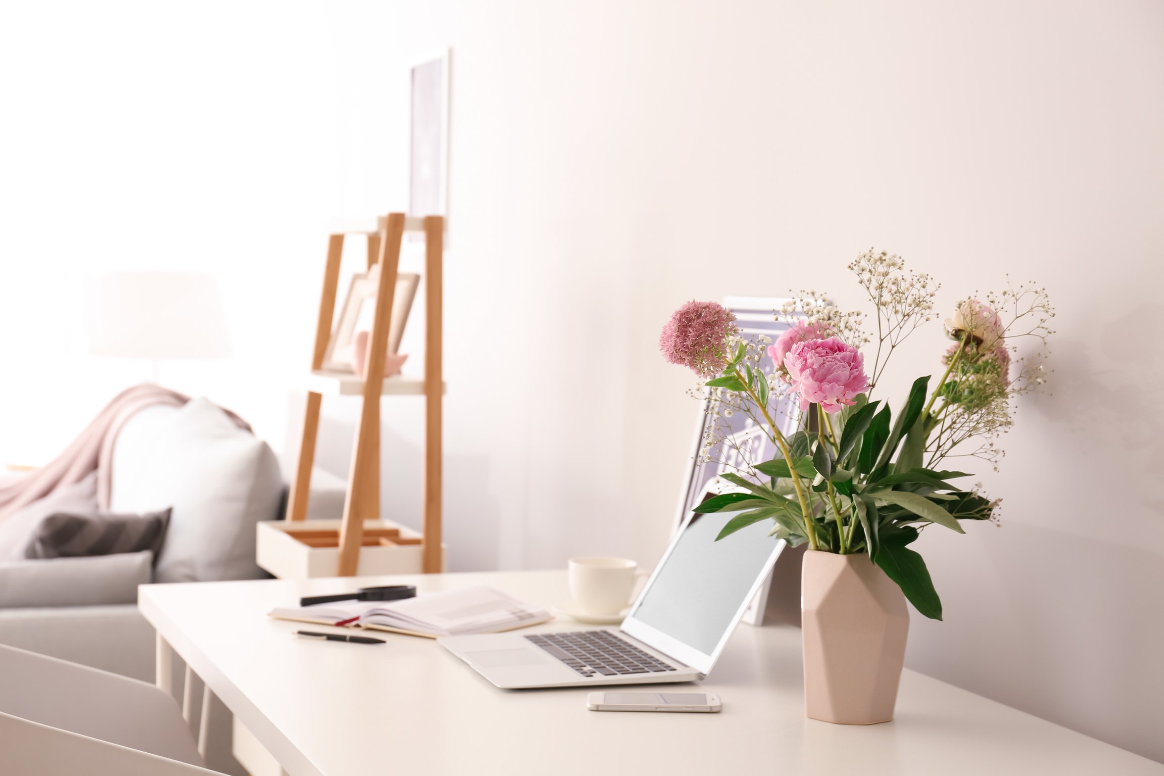 Vase with Beautiful Pink Flowers and Laptop on Table